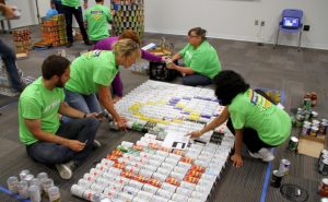 CANstruction volunteers work together to build Olympic rings out of canned goods