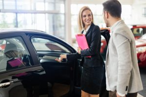 Car dealership sales person showing a customer a vehicle