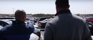 man on car lot pointing out cars that used floor plan financing for used car dealers