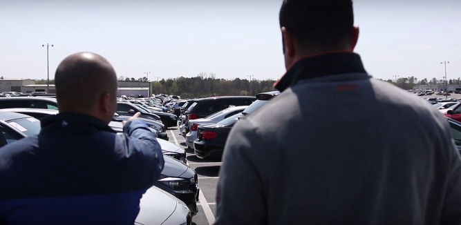 man on car lot pointing out cars that used floor plan financing for used car dealers