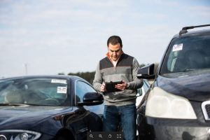 Dealer walking through a car lot with a tablet