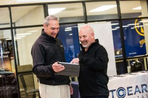 Dealer talking to a representative about floor plan lending with the aid of a tablet.