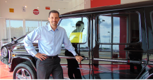 Garrick Hatfield posing by a car at his dealership